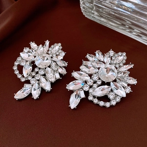 Macro view of crystal geometric flower earrings on dark silk, vintage evening style