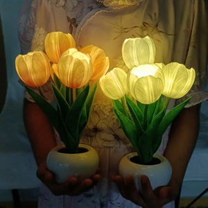 Warm glow LED tulip night light in ceramic pot held by hands for cozy bedroom decor
