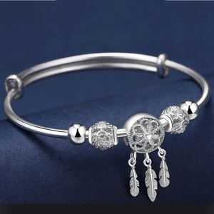 Elegante bracciale acchiappasogni in argento con piume e perline su fondo blu