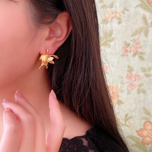 Dettaglio ravvicinato di un orecchino a fiore dorato vintage su una modella