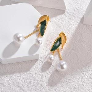 Detail of vintage bohemian dangle earrings with gold leaves, green enamel, and pearls