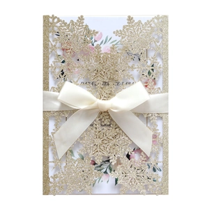 Detail of laser cut gold glitter snowflake wedding card with a cream white ribbon bow