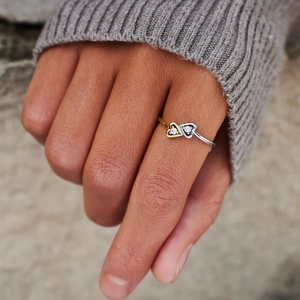 Macro view of two-tone S925 silver heart ring with zircon stones worn on model finger