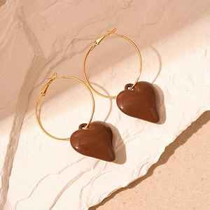 Macro shot of vintage chocolate resin heart charms on golden hoop earrings over white stone