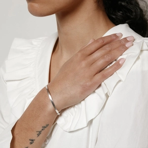 Detailed view of a minimalist silver flat snake chain bracelet on a model wrist