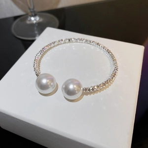 Detailed view of silver choker with faceted texture and large white pearls on display