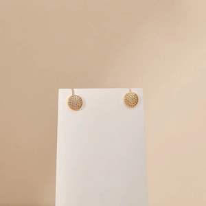 Macro detail of round gold-plated stud earring with micro-paved sparkling zircon stones