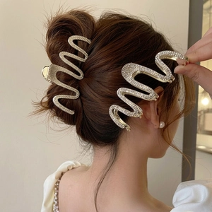 Sparkling wavy metal hair claw with rhinestones shown on elegant brunette updo hairstyle