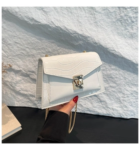 Detail of white crocodile pattern shoulder bag with gold chain strap and metal lock