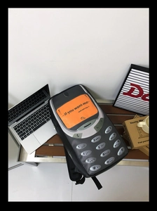 Detail of retro cellphone shaped backpack with orange screen and numeric keypad design