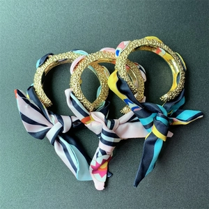 Detailed macro view of three matte gold textured bangles with colorful silk ribbon wraps