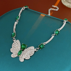 Détail du collier papillon argenté avec zircon vert dans un écrin à bijoux bleu