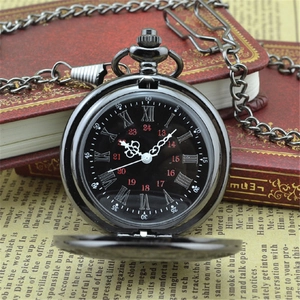 Vintage black alloy pocket watch with roman numerals on retro book background