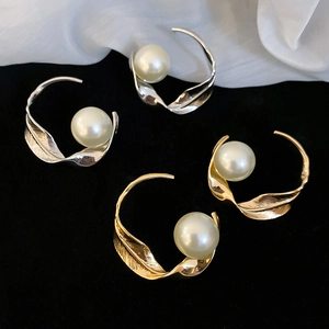 Dettaglio di orecchini a cerchio intrecciati con perla in oro e argento su velluto nero