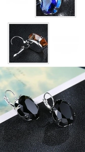 Detailed view of oval zircon earrings in dark blue, amber, and black with lever back hooks