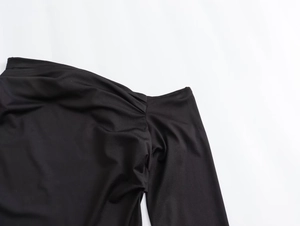Close-up of elegant pleated shoulder detail on a black nylon asymmetric maxi dress