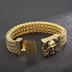Close-up of golden stainless steel braided bracelet with punk skull head buckle detail