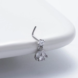 Detailed close-up of L-shaped silver nose stud with marquise zircon pendant on white ceramic