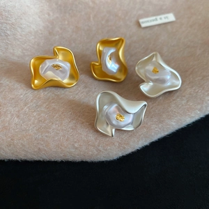 Detailed macro view of irregular matte flower stud earrings with central pearl and gold foil