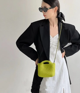 Neon green woven mini bucket bag worn by model with black chain strap and top handle