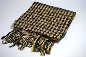Close-up of a folded khaki and black shemagh scarf with traditional weave and fringe