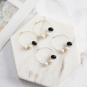 Retro S925 silver hoop earrings with obsidian and pearls on a white marble tray