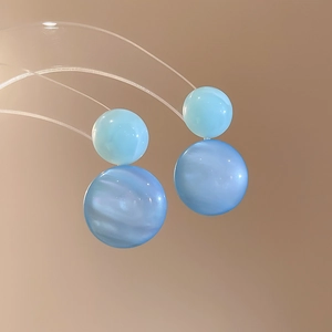 Detail of round blue resin stud earrings featuring double spheres with cat-eye texture