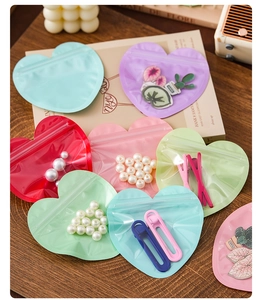 Colorful heart-shaped resealable jewelry bags displayed on a cozy wooden background