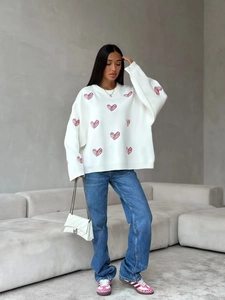 White long-sleeve knit sweater with red heart patterns and stylish blue denim jeans