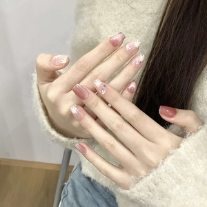 Press-on nails featuring pink gradient, white daisy art, and shimmering glitters in long oval shape