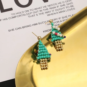 Handmade Christmas tree pearl earrings in green and gold on a stylish golden tray
