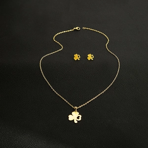 Detail of 18K gold clover jewelry set with hollow heart motifs on black leather base