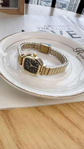 Detailed macro of stainless steel clasp on a golden square watch with black dial