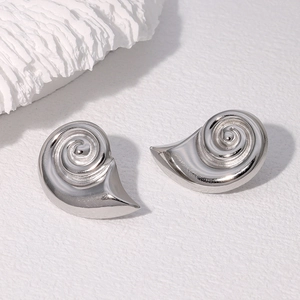 Macro shot of silver conch shell stud earrings on white textured background