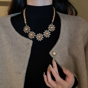 Detail of vintage flower pearl necklace set with crystal daisy accents on a model