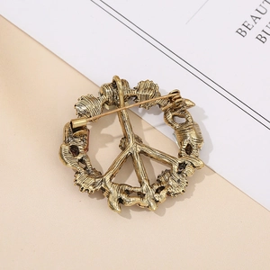 Vintage gold alloy peace sign brooch with rhinestone inlay and antique finish