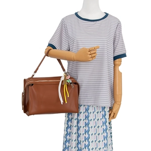 Brown leather handbag with colorful tassel and pink heart keychain on a wooden mannequin