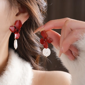 Close-up of red flower earrings with irregular pearls on a model wearing white sweater