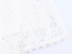Macro shot of delicate white lace fabric with floral embroidery and scalloped edges