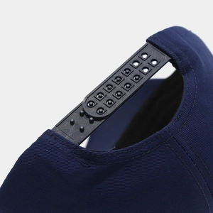 Gros plan détaillé sur l'attache réglable snapback d'une casquette en coton bleu marine