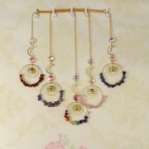 Five assorted sun and moon crystal suncatchers with colorful healing stones hanging on a wall