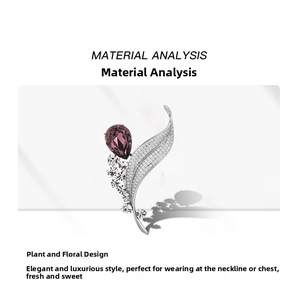Detailed close-up of leaf brooch featuring inlaid crystals and a purple pear-shaped gemstone