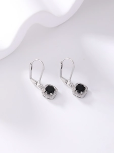 Detailed macro view of silver earrings featuring a round black gemstone with halo set diamonds