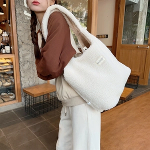 Detail of soft white faux shearling tote bag featuring a minimalist side woven label