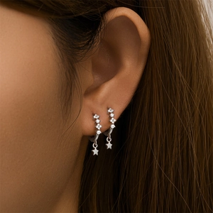 Close-up of S925 silver hoop earrings with clear diamonds and small star pendants