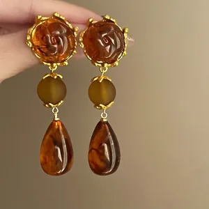 Detail view of retro earrings with rose relief, brown beads and amber resin pendants