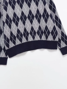 Macro detail of navy and grey argyle pattern knit top showing ribbed cuff and hem textures