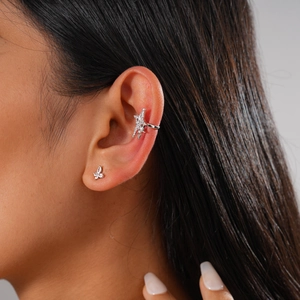 Close-up of a silver butterfly stud and star ear cuff set with zircon stones on a model