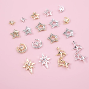 Golden and silver star and moon nail art charms with sparkling rhinestones on pink surface