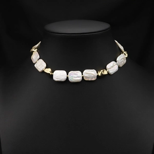 Baroque pearl necklace with square white pearls and gold accents on black display bust